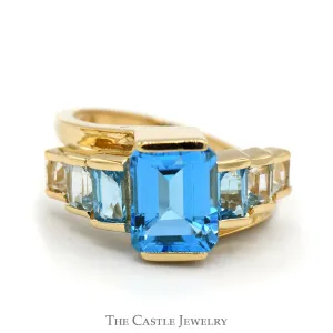 Emerald Cut Blue Topaz Ring with Graduated Design in 14k Yellow Gold Bypass Setting